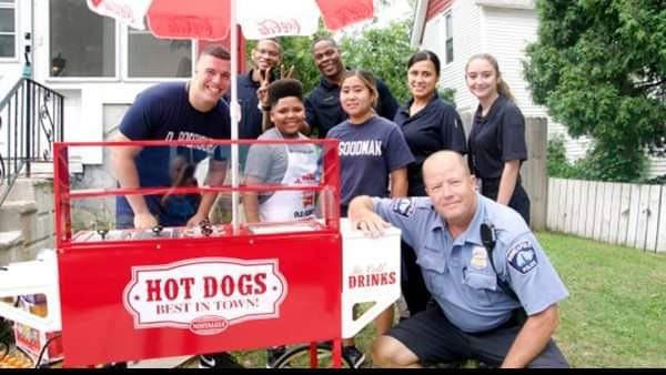Niño con empleados de salubridad en puesto de hot dogs