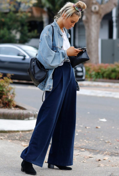 Mujer rubia mirando su celular en pantalones holgados