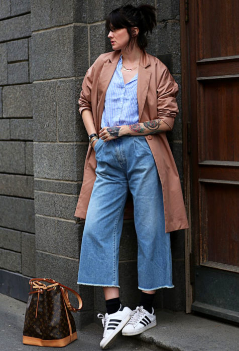 Chica en un pórtico con saco largo y pantalones holgados