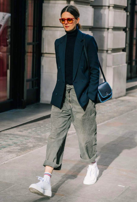 Mujer caminando con pantalones oversized y tenis blancos
