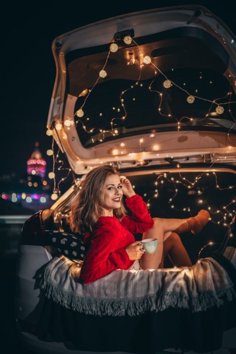 Chica en un automóvil decorado con luces en la cajuela