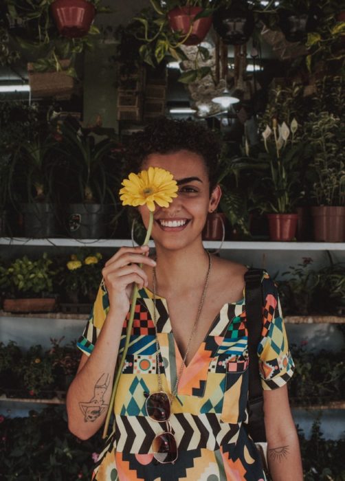 Chica sosteniendo un girasol mientras cubre su rostro