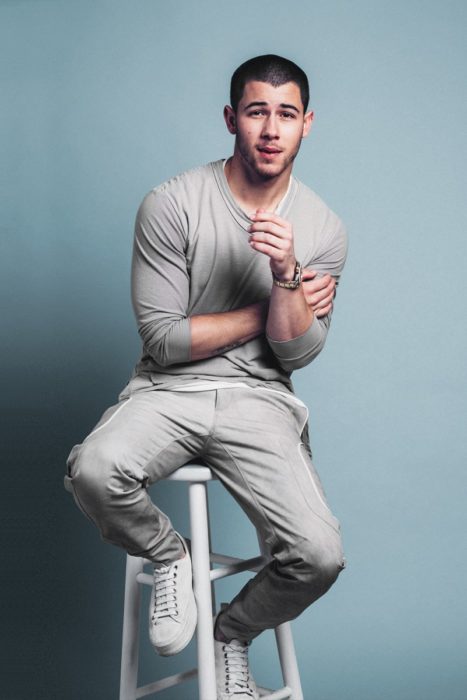 Nick Jonas sentado en un banquito posando para una foto de revista