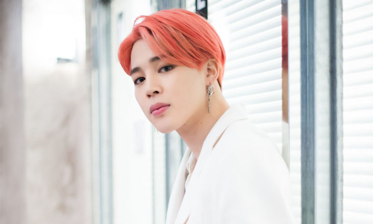 Jimin con cabello rosa y traje blanco, posando para una sesión de fotos