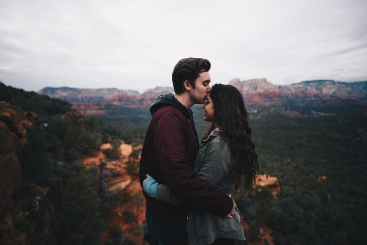 Pareja de novios abrazados y sonrientes en una montaña