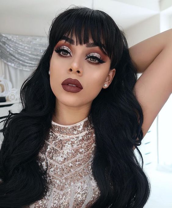 Chica mostrando maquillaje en rosas, rojos y dorados