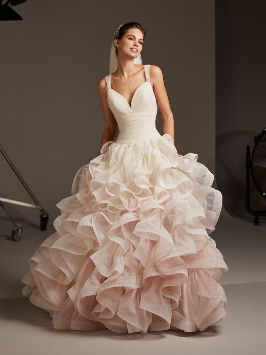 Chica con un vestido de novia de colores degradados en rosa con varias capas de tul