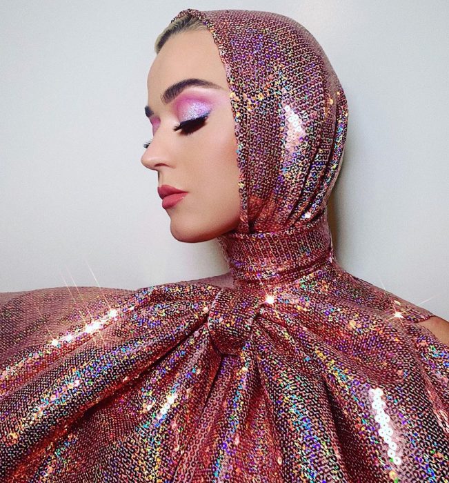Katy Perry usando un atuendo brillante con un moño gigante 