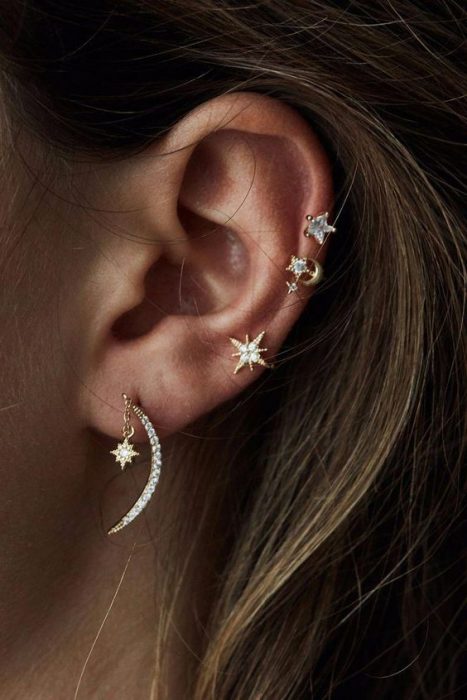 Chica mostrando sus pequeños pendientes en forma de estrella y luna