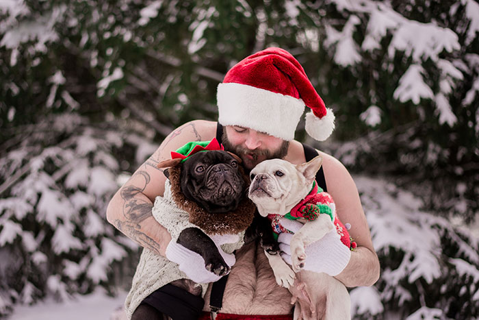 Hombre vestido de Santa Claus cargando a dos perritos mientras posan para la sesión de fotos de un calendario