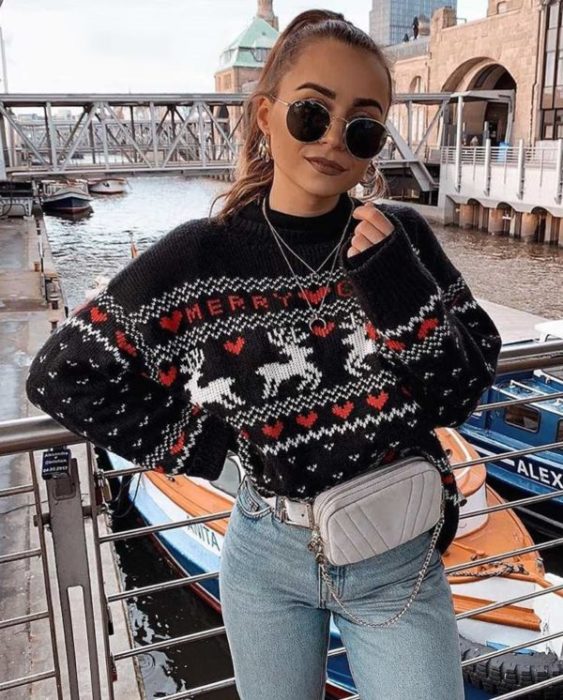 Chica usando un ugly sweter de color negro con jeans y una riñonera