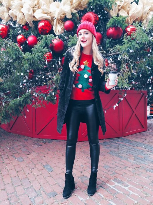 Chica usando un feo suéter navideño con chaqueta negra y leggins de cuero