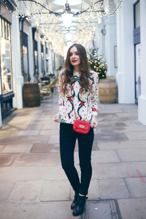 Chica usando un feo suéter navideño con jeans y botines