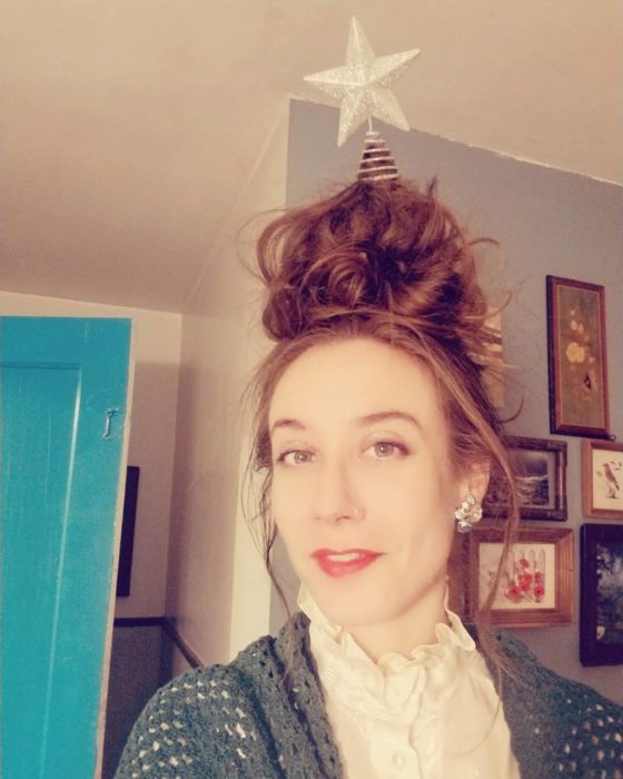Chica con chongo alto decorado con una estrella navideña plateada
