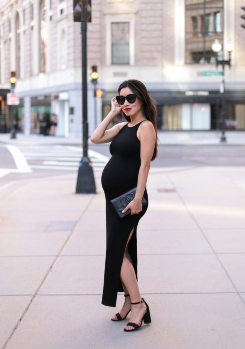 Mujer embarazada en una sesión de fotos usando un vestido negro largo con escote