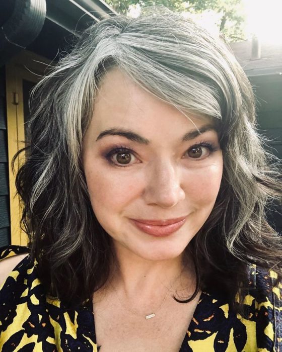 Chica tomándose una selfie para mostrar las canas en la parte superior de su cabello 