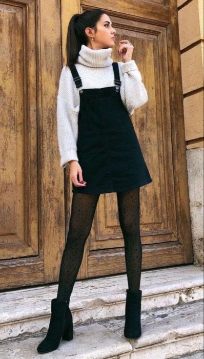Chica usando un overol de color negro con un suéter de color beige