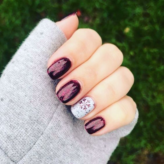 Manicura roja con glitter y decorada con un copo de nieve rojo