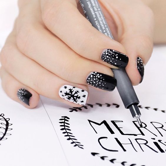 Uñas en blanco y negro decoradas con copos de nieve negros