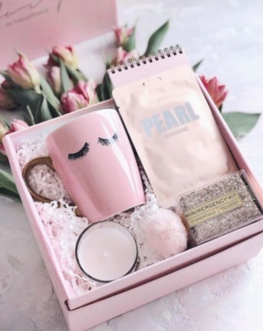 Caja de regalo con una taza rosa, velas y una agenda