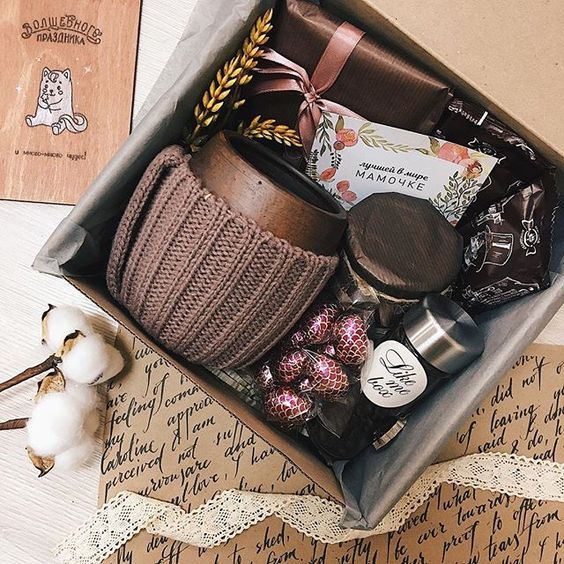 Caja de cartón con una taza, chocolates y un porta vaso de estambre