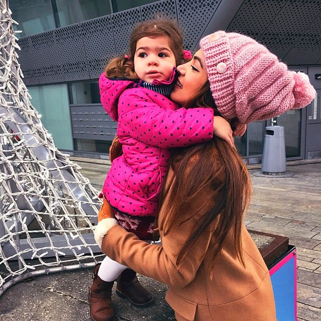 Mujer abrazando a una niña y besándola en la mejilla