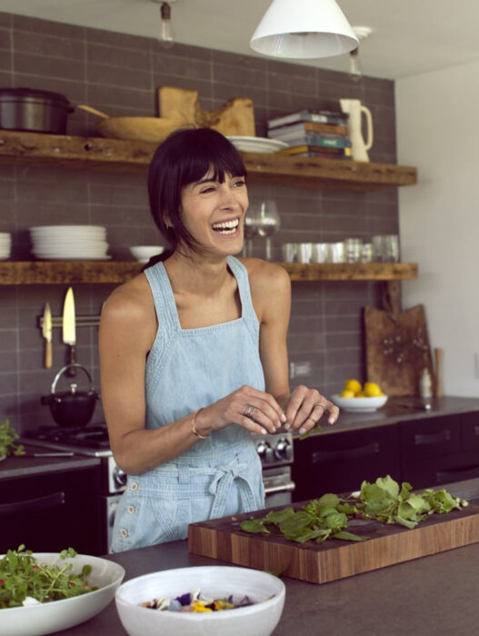 Mujer castaña sonriendo en la cocina mientras cocina
