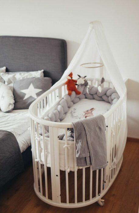 Cuna estilo moisés en color blanco colocada a un lado de la cama principal