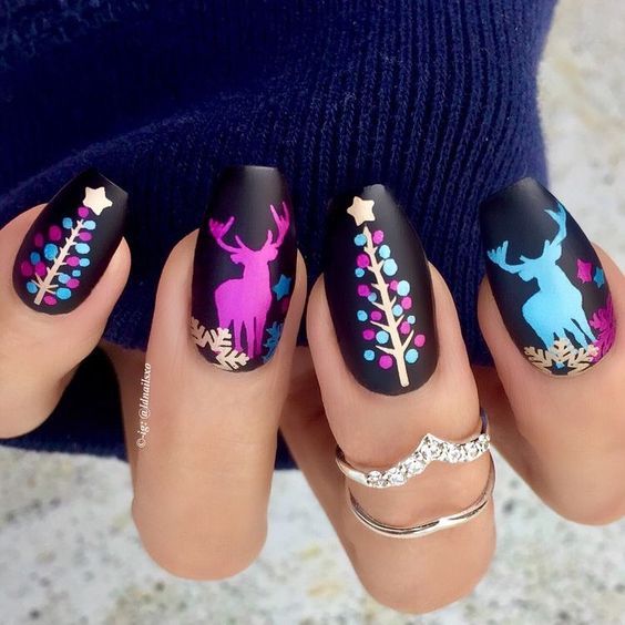 Uñas pintadas con base en tono negro y figuras navideñas en colores fluorescentes; diseños de manicuras navideñas
