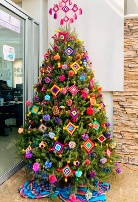 Decoración de Navidad con temática mexicana; árbol navideño con artesanías, ojo de Dios, arte huichol,