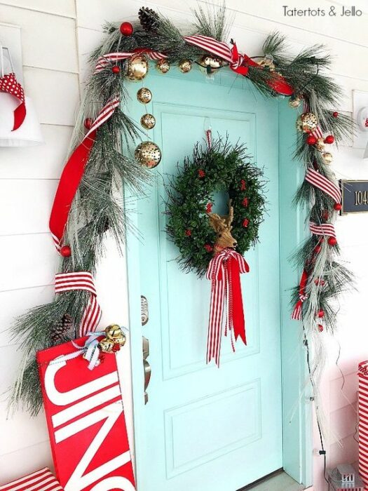 Puerta color azul Tiffany en una casa blanca con hojas de pino y una corona con un lazo rojo