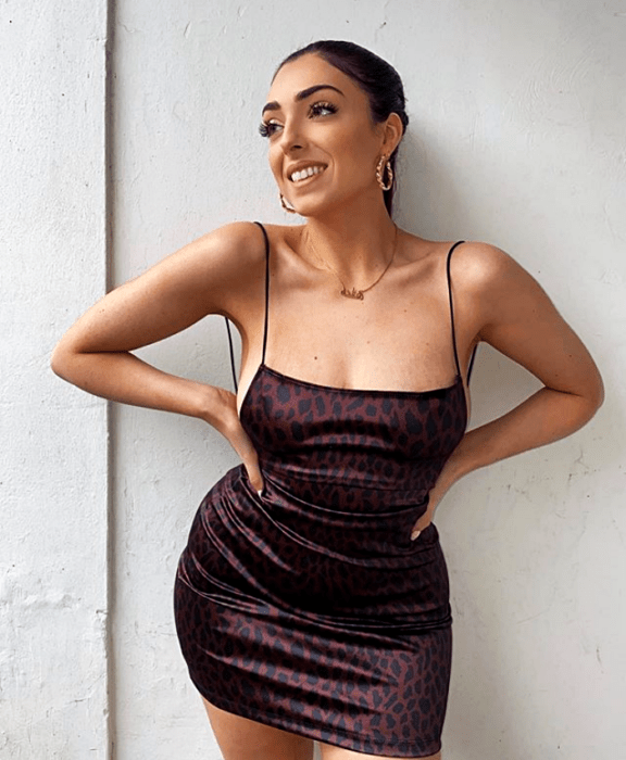Chica de cabello castaño en un vestido ceñido de tirantes con estampado animal print en negro y café