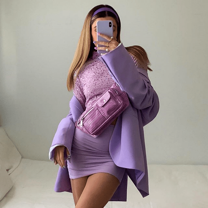 chica usando top morado con saco morado, falda morada y bolso de mano color fucsia