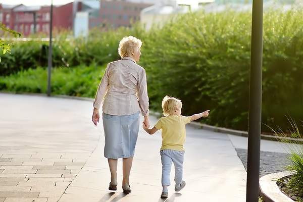 Abuela camina con su nieto pequeño de la mano
