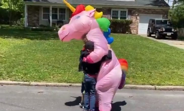 Nietos abrazando a su abuela disfrazada de unicornio