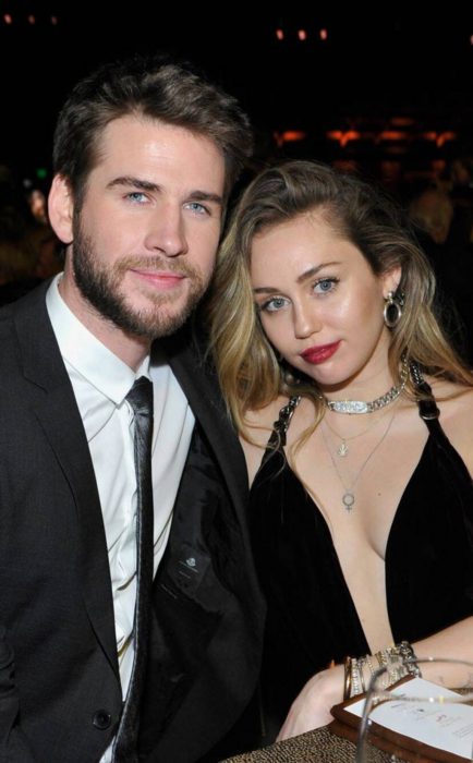 Miley Cyrus y Liam Hemsworth posando para una foto durante una cena
