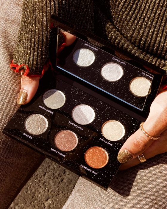 Manos sosteniendo paleta de sombras metalizadas con packaging negro