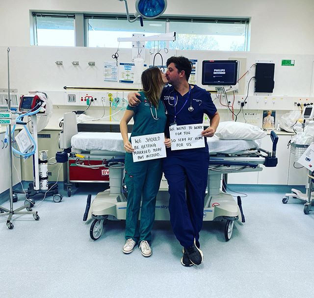 Pareja de doctores sosteniendo un cartel y besándose en un quirófano