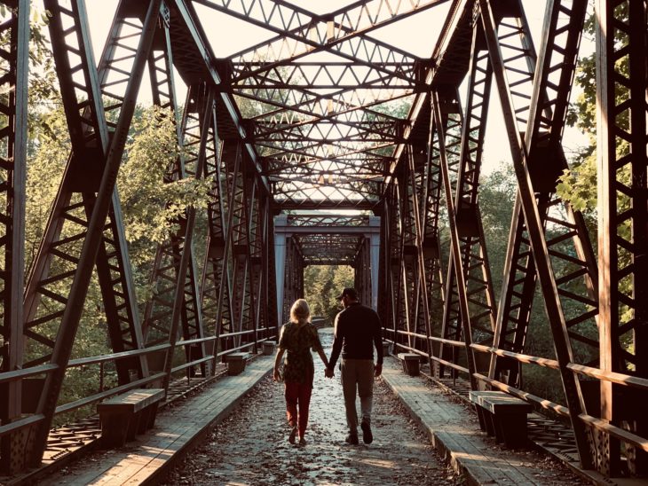 Escena de la película A Quiet Place 2 con una pareja caminando por un puente de madera