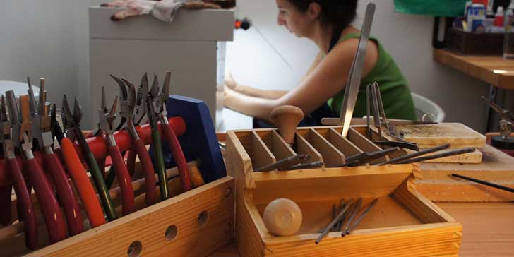 Mujer revisando cajones con material para elaborar joyería