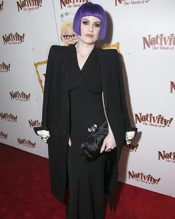 Kelly Osbourne con cabello lila y un outfit negro en una alfombra roja