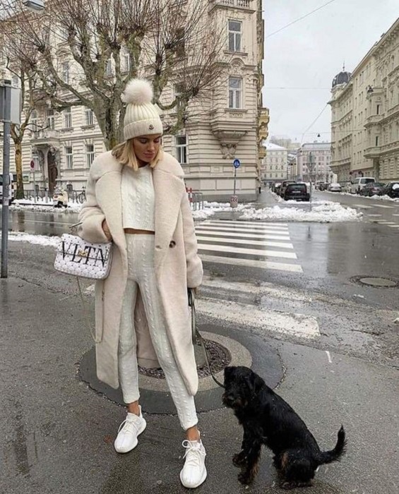 Chica luciendo un total white look con tenis, leggings y crop top tejidos, acompañado de abrigo y gorro con pompones