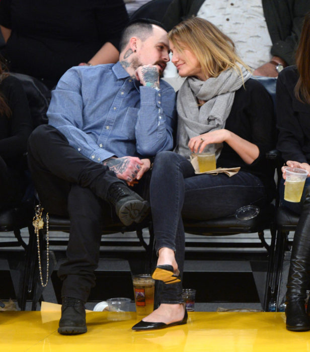 Cameron Diaz y Benji Madden sentados mirándose fijamente durante un partido de basketball