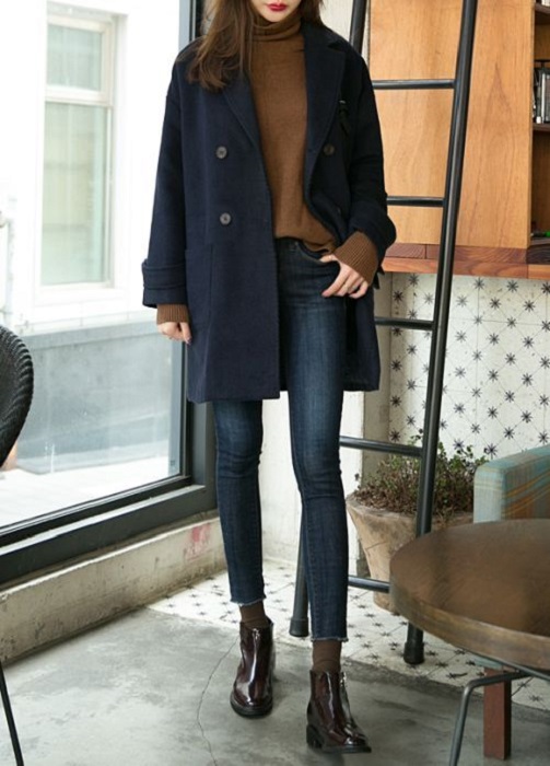 Outfit para la oficina de otoño-invierno de abrigo color azul marino, suéter color camel, jeans y botines negros