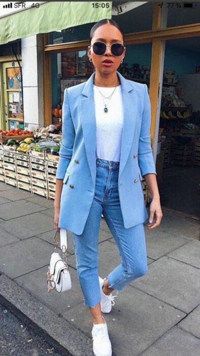 Chica completamente vestida de azul con zapatos deportivos y bolso blanco