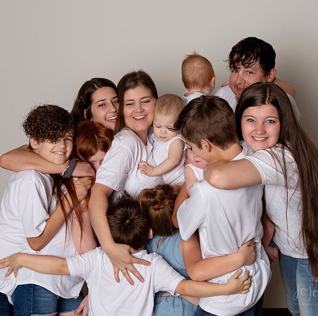 Mujer en una sesión de fotos abrazando a sus 11 hijos