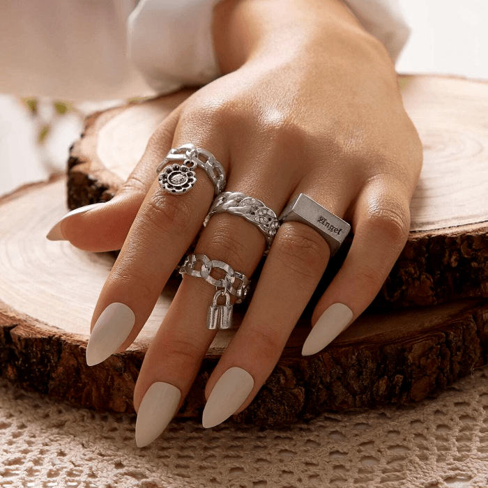anillos plateados de diferentes diseños, manicura, uñas pintadas de color blanco mate