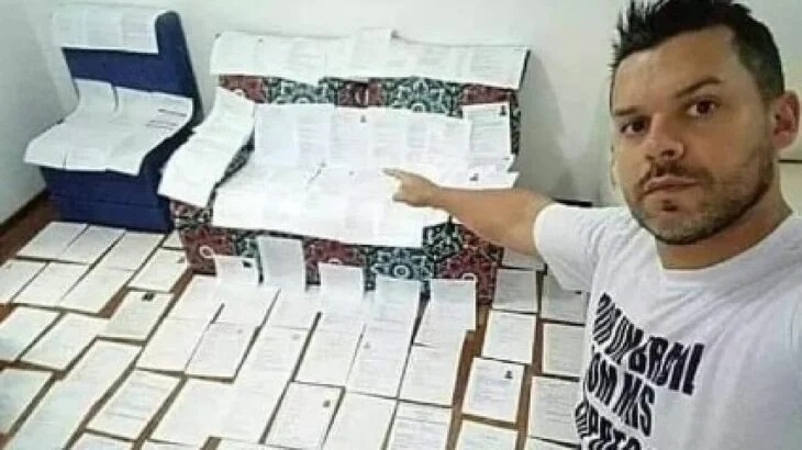Hombre desarrugando hojas de papel que encontró en la basura