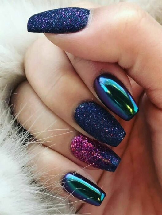 Chica con las uñas en un diseño metálico de color azul con toques rosas y morados