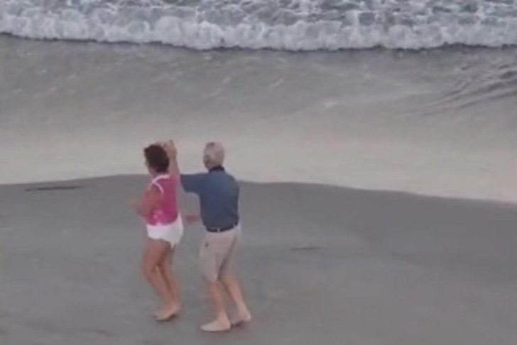 Pareja de ancianos baila alegremente en la playa